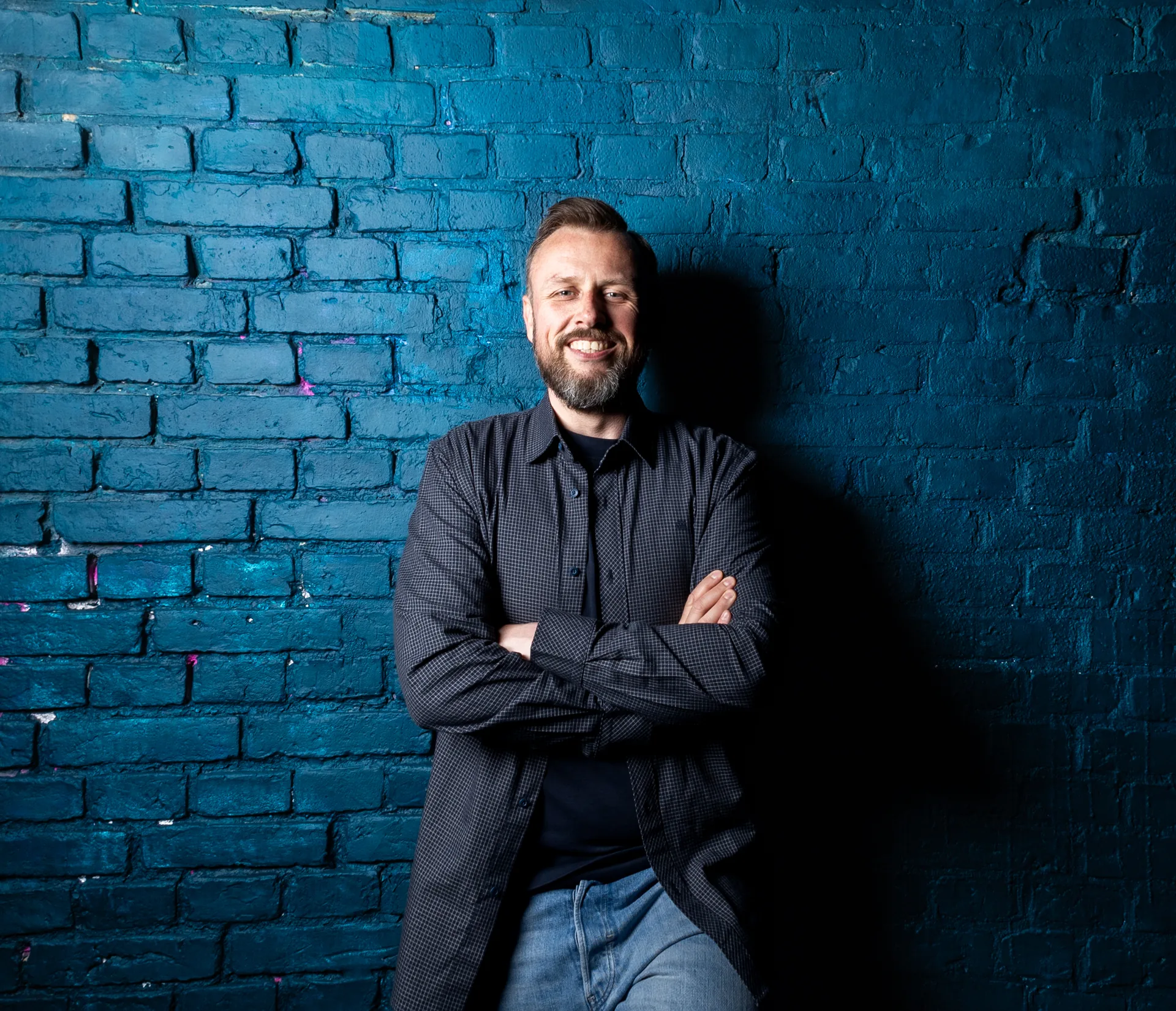 Simon Bode – Porträt vor einer blauen Backsteinwand